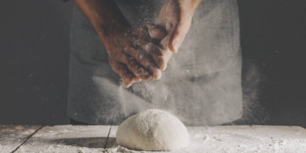 Chef making fresh dough for baking bread. Closeup with copy space. Horizontal.